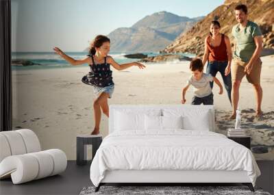 Happy young white family on holiday exploring a beach together, full length Wall mural