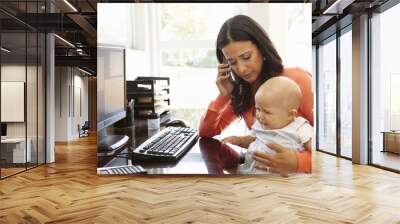 hispanic mother with baby working in home office Wall mural