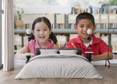 Kindergarten children sitting at desk and writing in classroom Wall mural