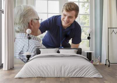 Male care worker serving dinner to a senior man at his home Wall mural