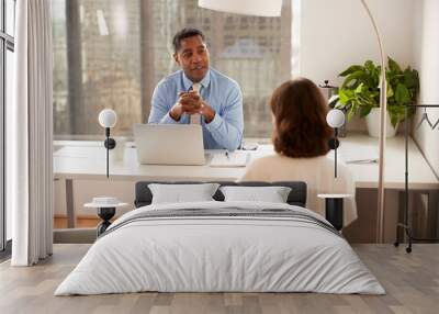 male financial advisor in modern office sitting at desk meeting female client Wall mural