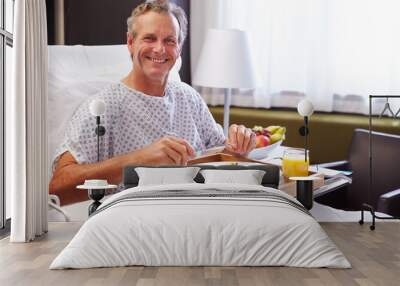 male patient in hospital bed eating meal from tray Wall mural