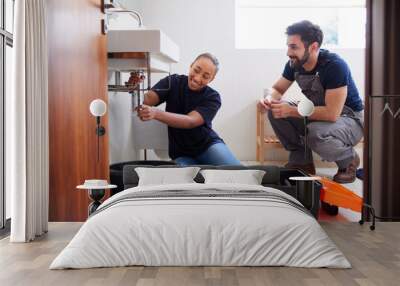 Male Plumber Teaching Female Apprentice To Fix Leaking Sink In Home Bathroom Wall mural