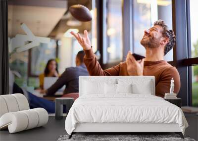 Mature Businessman With Feet On Desk In Office Talking Into Mic Of Mobile Phone Catching Football Wall mural