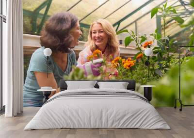 Mature Same Sex Female Couple Working In Greenhouse Looking After Vegetables And Plants Together Wall mural