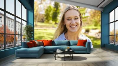 Mid thirties white woman smiling to camera in a park Wall mural