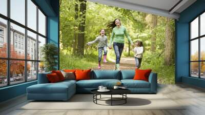 Mother running along woodland path with 2 childrren Wall mural