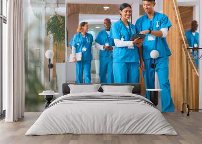 Multi Cultural Medical Team Wearing Scrubs Walking Along Corridor In Modern Hospital  Wall mural