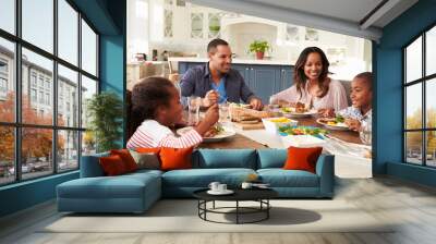 Parents and their two children eating at kitchen table Wall mural