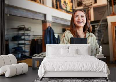 Portrait Of Female Owner Of Fashion Store Using Digital Tablet To Check Stock In Clothing Store Wall mural