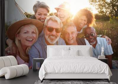 Portrait Of Mature Friends By Tent On Camping Vacation Against Setting Sun Wall mural