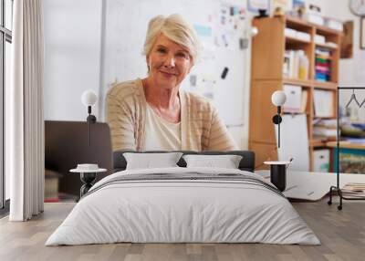 Portrait of senior female teacher working at her desk Wall mural