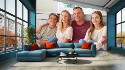 Portrait Of Smiling Family Relaxing On Seat At Home Wall mural