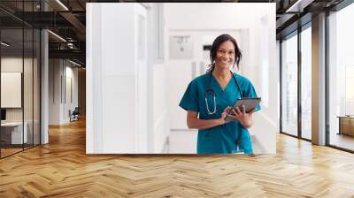 Portrait Of Smiling Female Doctor Wearing Scrubs In Hospital Corridor Holding Digital Tablet Wall mural