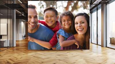 Portrait Of Smiling Hispanic Family With Parents Giving Children Piggyback Rides In Garden At Home Wall mural