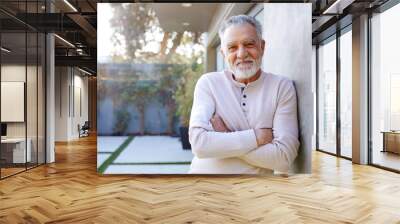 Portrait Of Smiling Retired Senior Hispanic Man In Garden At Home Against Flaring Sun Wall mural