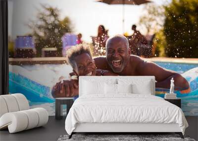 Portrait Of Smiling Senior Couple On Summer Holiday Relaxing In Swimming Pool On Inflatable Wall mural