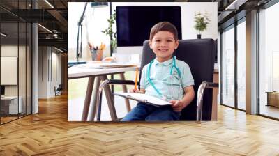 Portrait Of Smiling Young Boy Sitting In Chair In Office Pretending To Be Doctor Wall mural