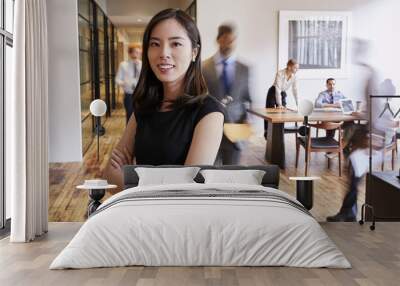 Portrait of young Asian woman in a busy modern workplace Wall mural