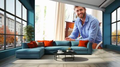 Portrait ofÿa smiling young man sitting in a room Wall mural