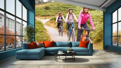 Pre-teen girl riding mountain bike with her parents during a family camping trip, close up Wall mural