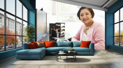 senior hispanic woman working on computer at home Wall mural