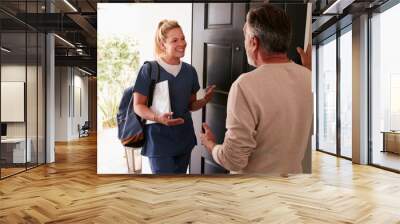 Senior man opening his front door to a female healthcare worker making a home health visit Wall mural