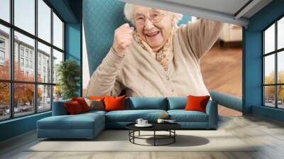 senior woman celebrating in chair at home Wall mural