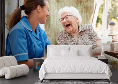 Senior Woman Sitting In Chair And Laughing With Nurse In Retirement Home Wall mural