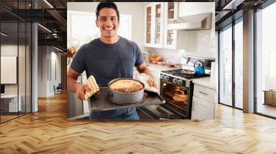 Smiling millennial Hispanic man standing in kitchen presenting the cake he has baked to camera Wall mural