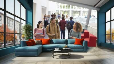 Students holding tablets and phone talk in university lobby Wall mural