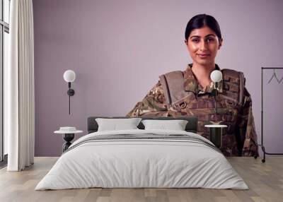 Studio Portrait Of Smiling Young Female Soldier In Military Uniform Against Plain Background Wall mural