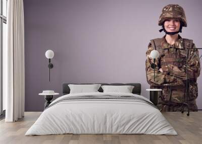 Studio Portrait Of Smiling Young Female Soldier In Military Uniform Against Plain Background Wall mural