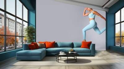 Studio Shot Of Woman Wearing Gym Fitness Clothing In Mid-Air Exercising On Grey Background Wall mural