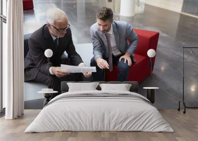 Two Businessmen Discuss Document In Lobby Of Modern Office Wall mural