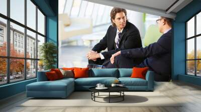 two businessmen sitting on sofa in modern office Wall mural