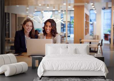 Two Businesswomen With Laptop At Desk In Open Plan Office Collaborating On Project Together Wall mural