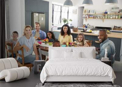 Two families having lunch together at home looking to camera Wall mural