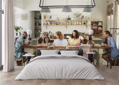 Two families having lunch together in the kitchen at home Wall mural