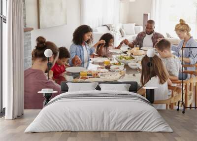 Two Families Praying Before Enjoying Meal At Home Together Wall mural