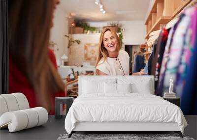 Two Female Friends Shopping In Independent Clothing Store Looking At Racks Wall mural