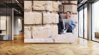 Two Female University Or College Students Sitting Against Wall In City Working On Digital Tablet Wall mural