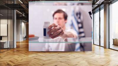 View Through Bathroom Cabinet Of Man Taking Medication From Container Wall mural