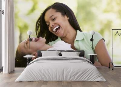 Woman and young girl outdoors embracing and laughing Wall mural