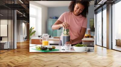 Woman Making Healthy Juice Drink With Fresh Ingredients In Electric Juicer After Exercise Wall mural