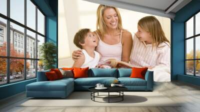 woman with two young children sitting in bed reading book and sm Wall mural