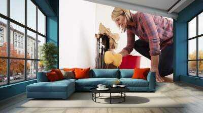 Worried woman mopping up water from a burst pipe with sponge Wall mural