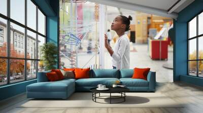 Young black girl looking at a science exhibit, close up Wall mural