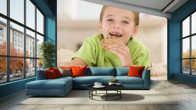 young boy eating cookie in living room smiling Wall mural