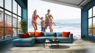 Young Family Running Along Beach on Holiday Wall mural